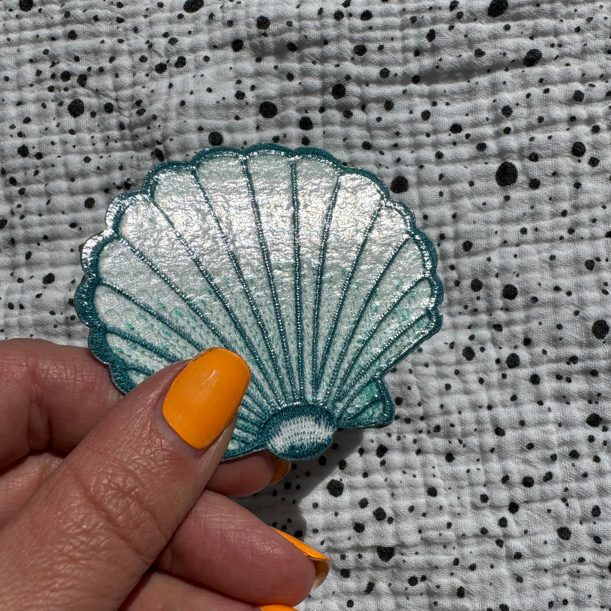Patch Venusmuschel in Türkis mit Glitzer, in der Hand gehalten