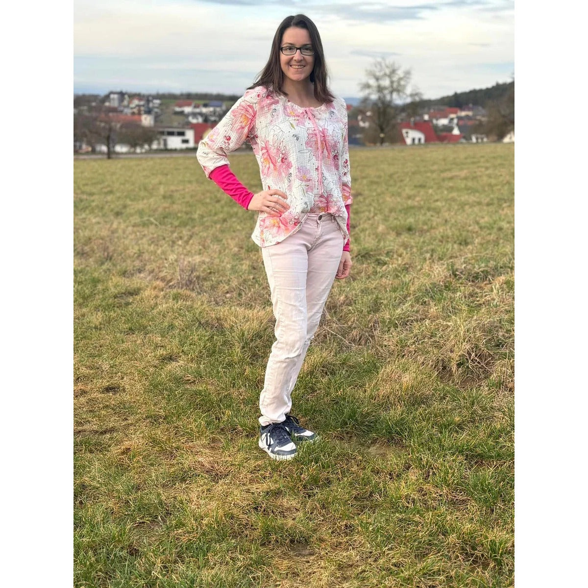 Miss Talia Schnittmuster – Frau in weißer Tunika mit pinken Ärmeln auf einem Feld (genähtes Designbeispiel)
