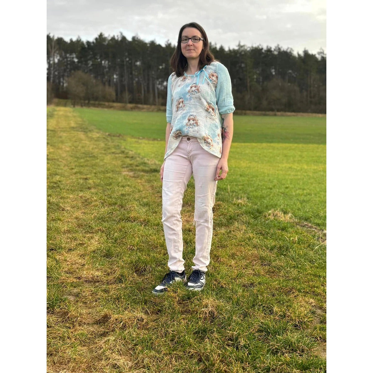 Miss Talia Schnittmuster – Frau in heller Tunika mit Jeans auf der Wiese (genähtes Designbeispiel)