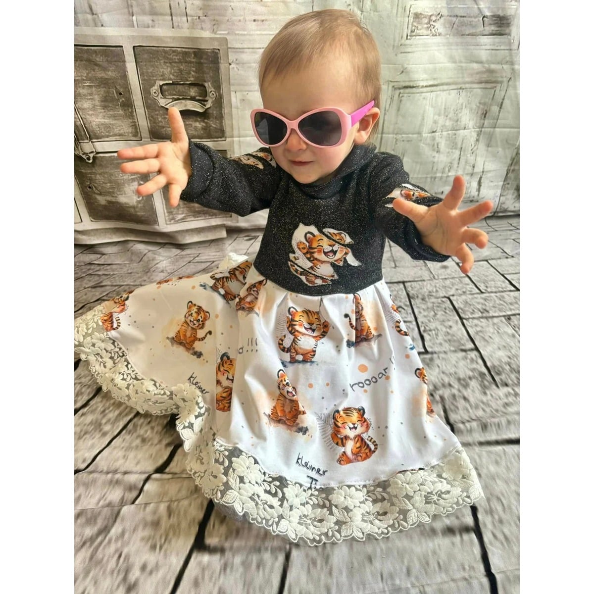 Winterzauberkleid Schnittmuster – Kleinkind mit Sonnenbrille im Winterzauberkleid mit Tiermotiven (genähtes Designbeispiel)