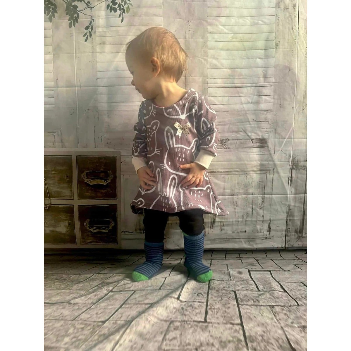 Sweet Tunika Kids Schnittmuster – Kleinkind in gemusterter Tunika in einem hellen Raum (genähtes Designbeispiel)