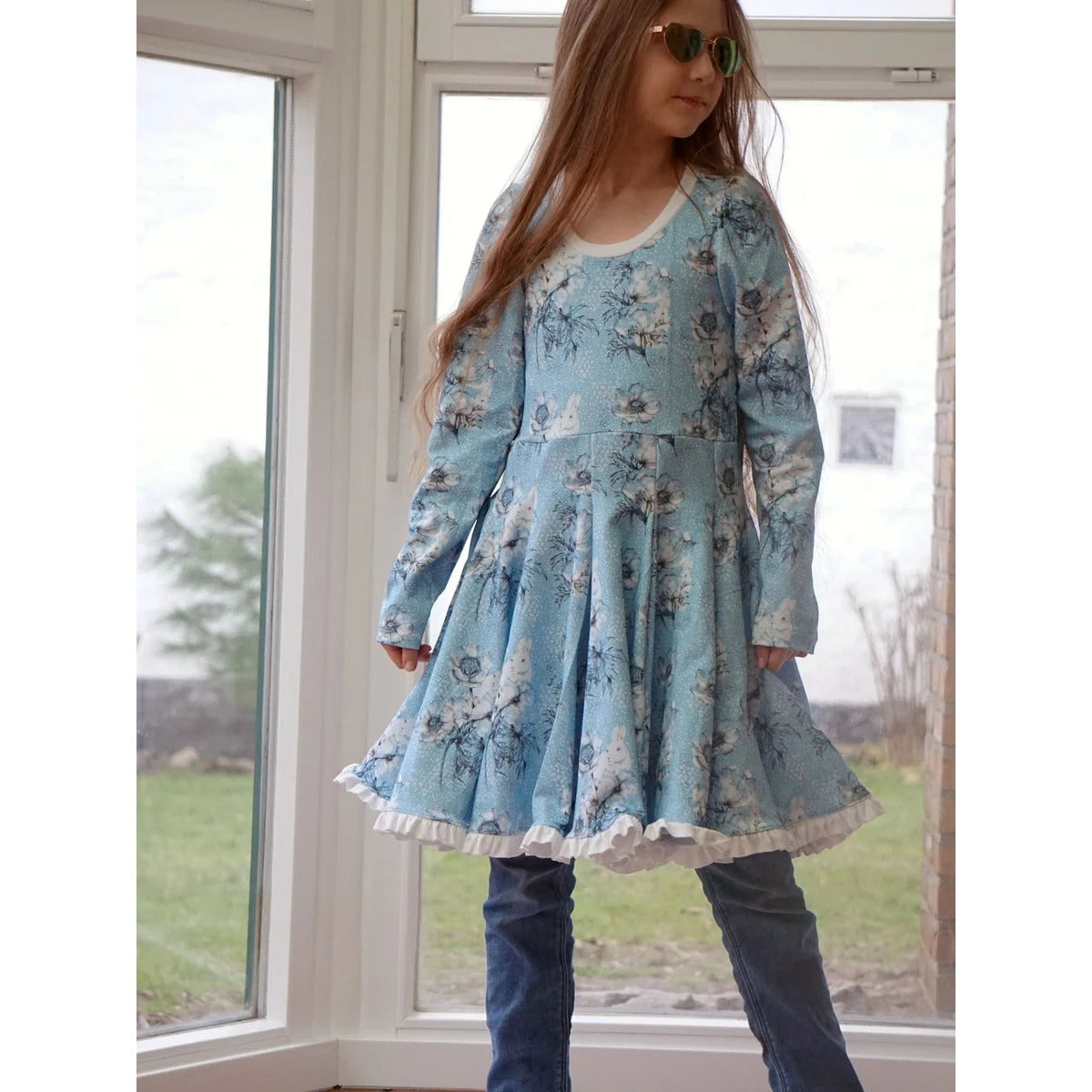WinterWUNDERkleid Schnittmuster – Mädchen im blauen Winterwunderkleid am Fenster (genähtes Designbeispiel)
