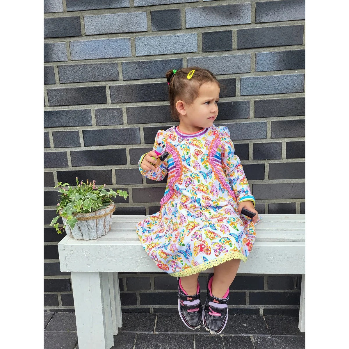 Kleid kleine Madame Schnittmuster – Kleinkind im geblümten Kleid auf einer Bank (genähtes Designbeispiel)