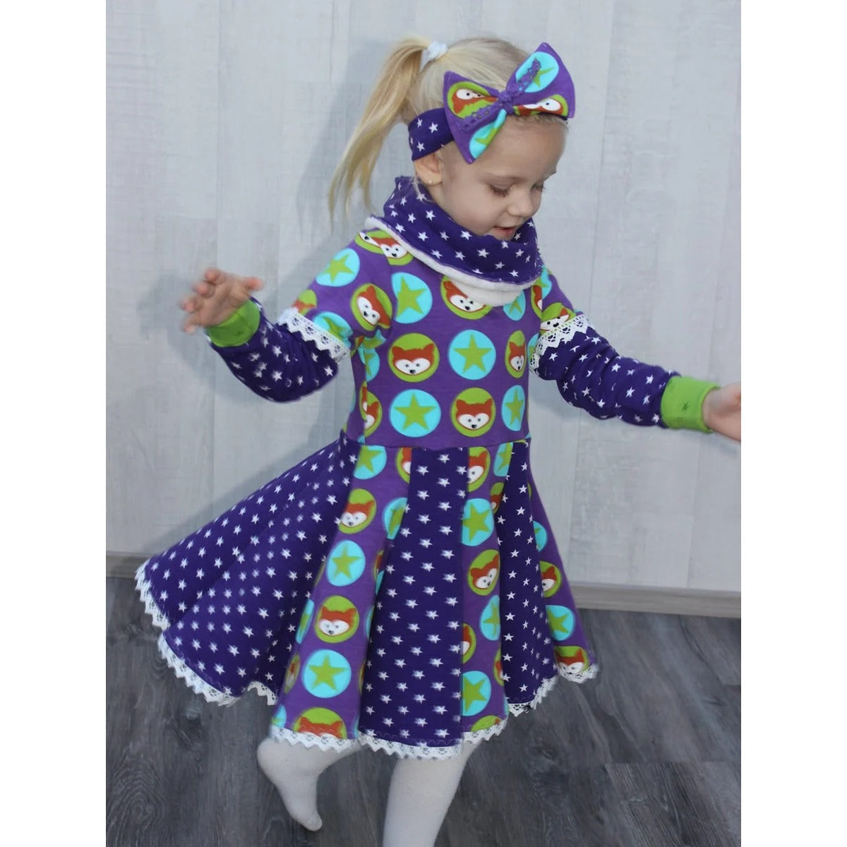 WinterWUNDERkleid Schnittmuster – Mädchen im lila gepunkteten Winterwunderkleid mit Sternen (genähtes Designbeispiel)