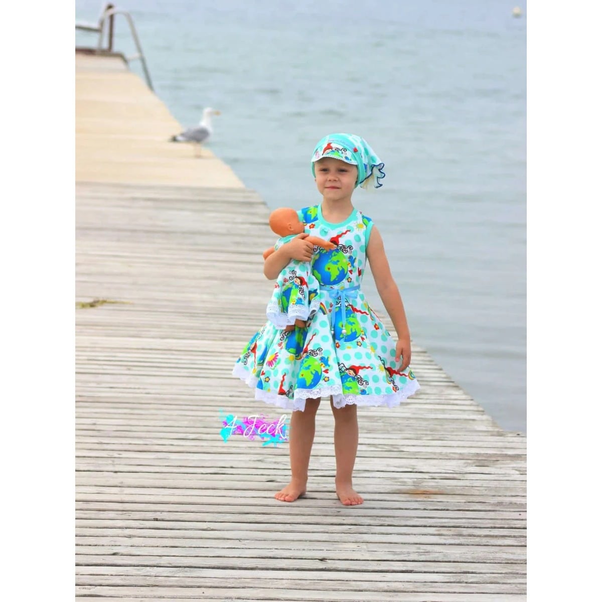WinterDreams Kleid Schnittmuster – Kind im geblümten Kleid auf einem Steg am Meer (genähtes Designbeispiel)