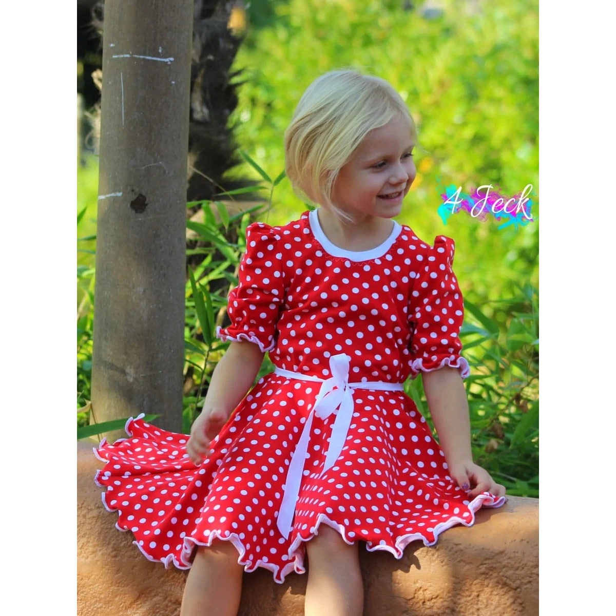 WinterDreams Kleid Schnittmuster – Mädchen im roten gepunkteten Kleid mit weißer Schleife (genähtes Designbeispiel)
