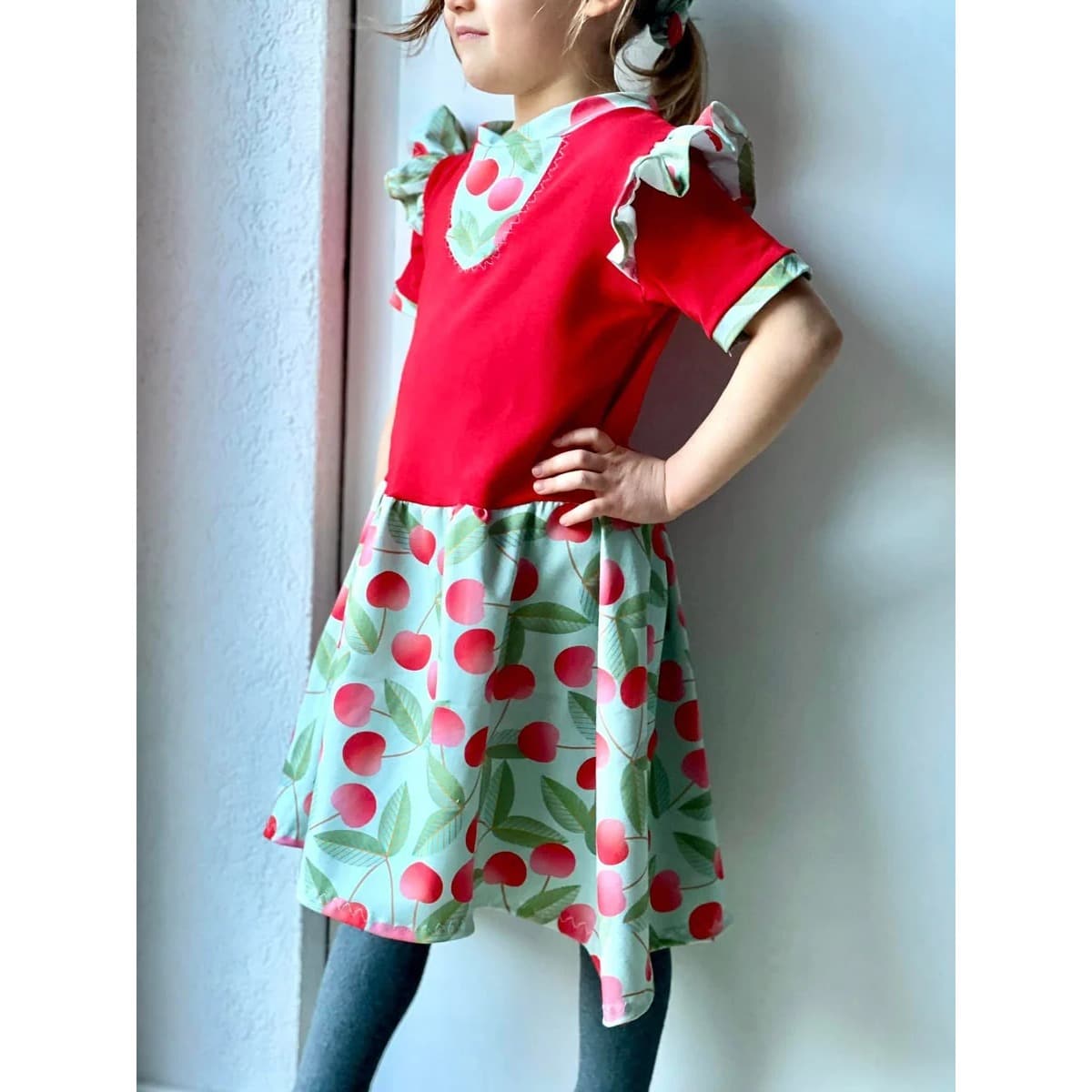 Ta Tunique Schnittmuster – Mädchen in roter Ta Tunique mit Kirschen-Rock (genähtes Designbeispiel)
