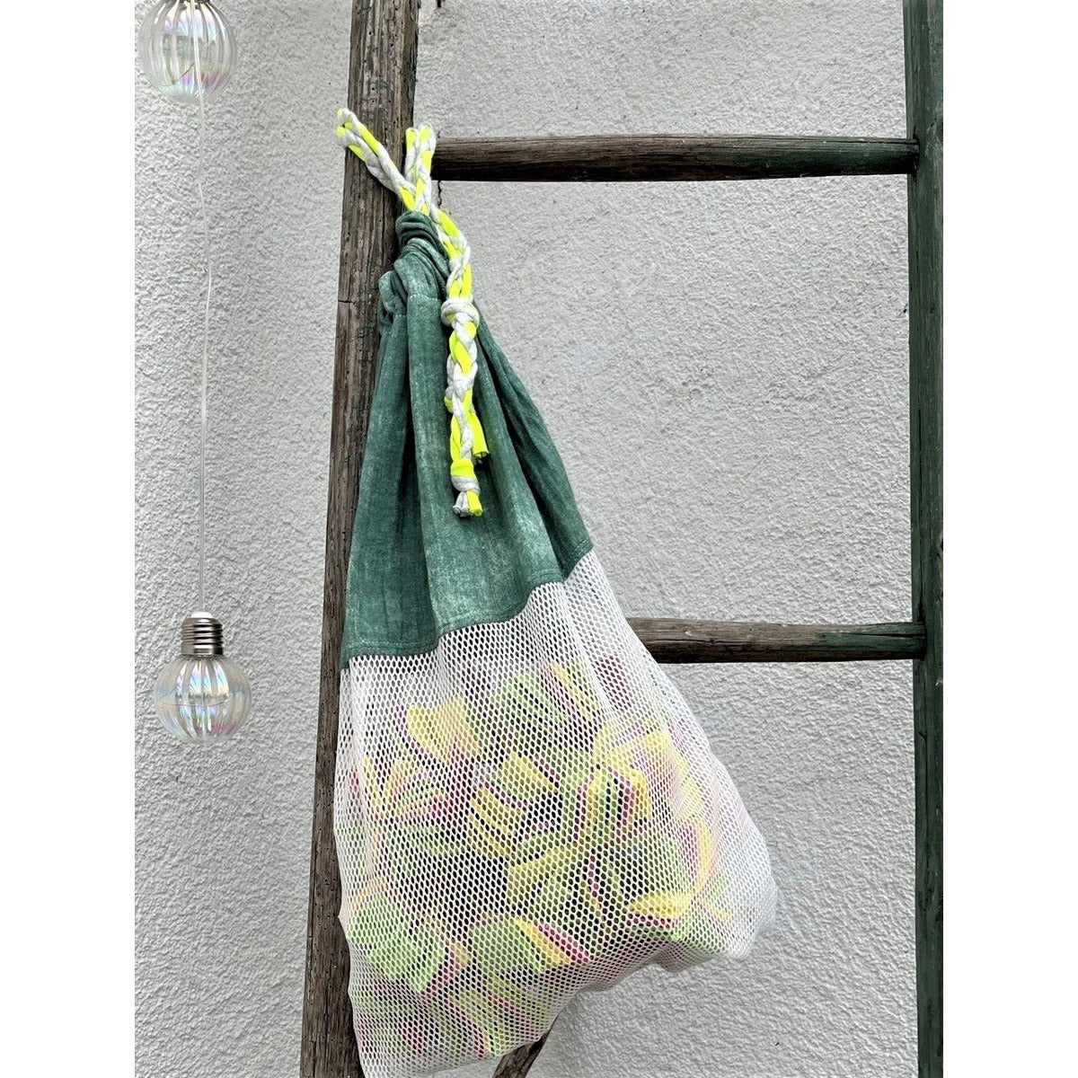 Freebook Sammelbeutel Strandgut Schnittmuster – grüner Netzbeutel mit Obst an einer Leiter hängend (genähtes Designbeispiel)