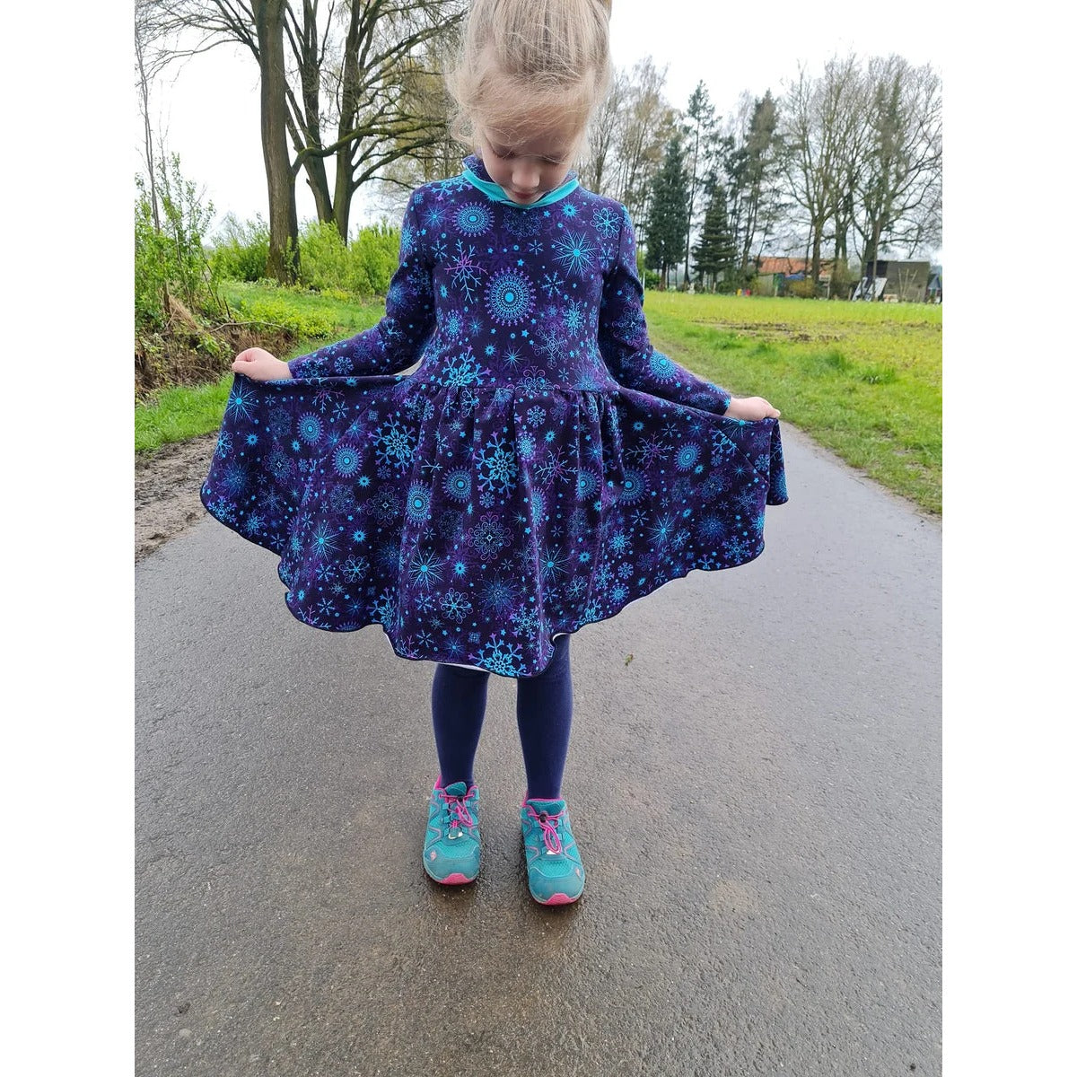 Winterzauberkleid Schnittmuster – Mädchen im dunkelblauen Winterzauberkleid auf einem Weg (genähtes Designbeispiel)