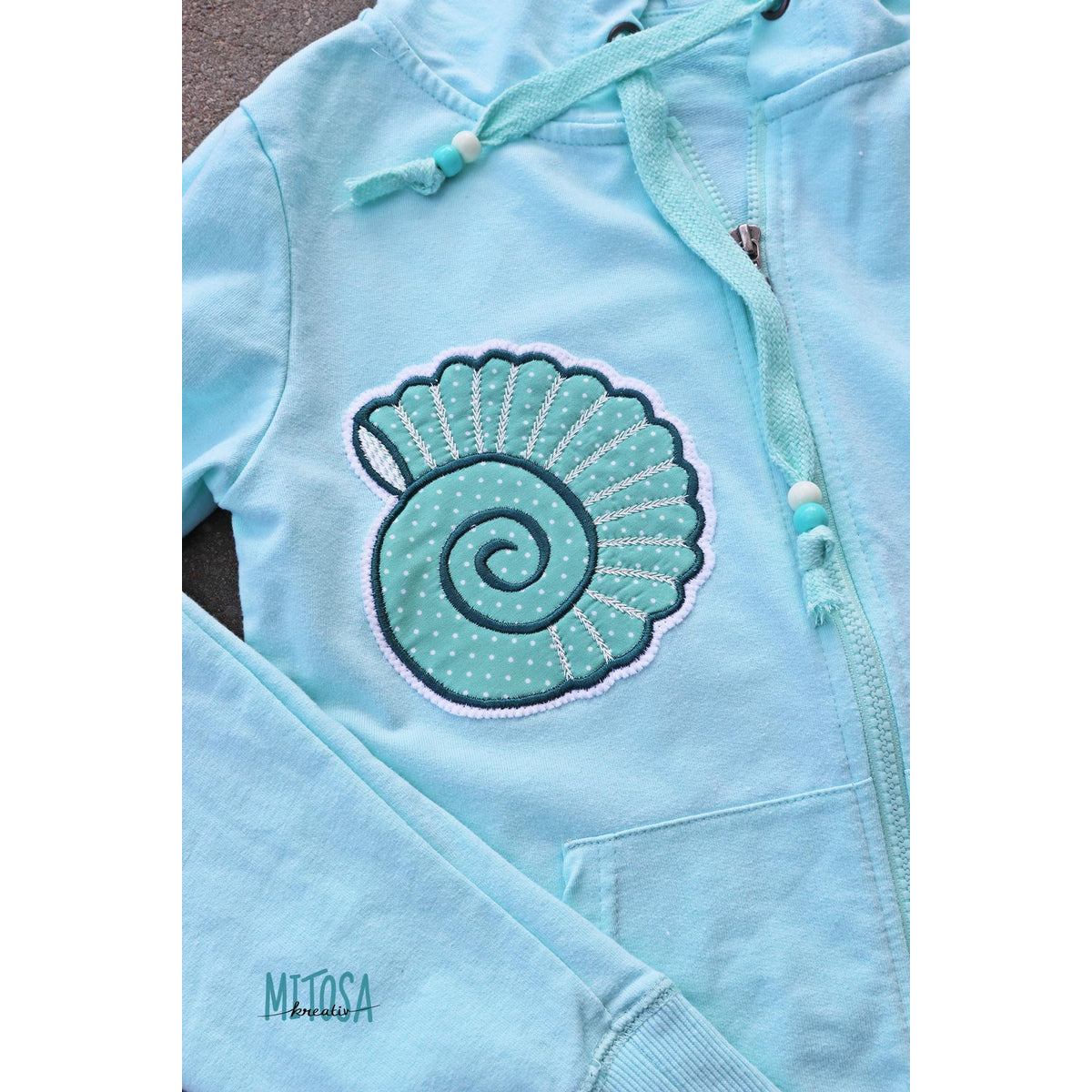 Maritime Applikations-Stickdatei – hellblauer Hoodie mit großer Muschel-Applikation