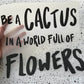 Bügelbild Be a cactus – Schriftzug „Be a cactus in a world full of flowers“ in Schwarz