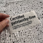 Bügelbild Certified patriarchy-free klein in Schwarz, ca. 10 x 4,5 cm, in der Hand gehalten