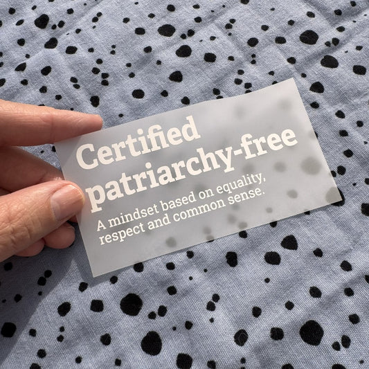 Bügelbild Certified patriarchy-free klein in Weiß, ca. 10 x 4,5 cm, in der Hand gehalten