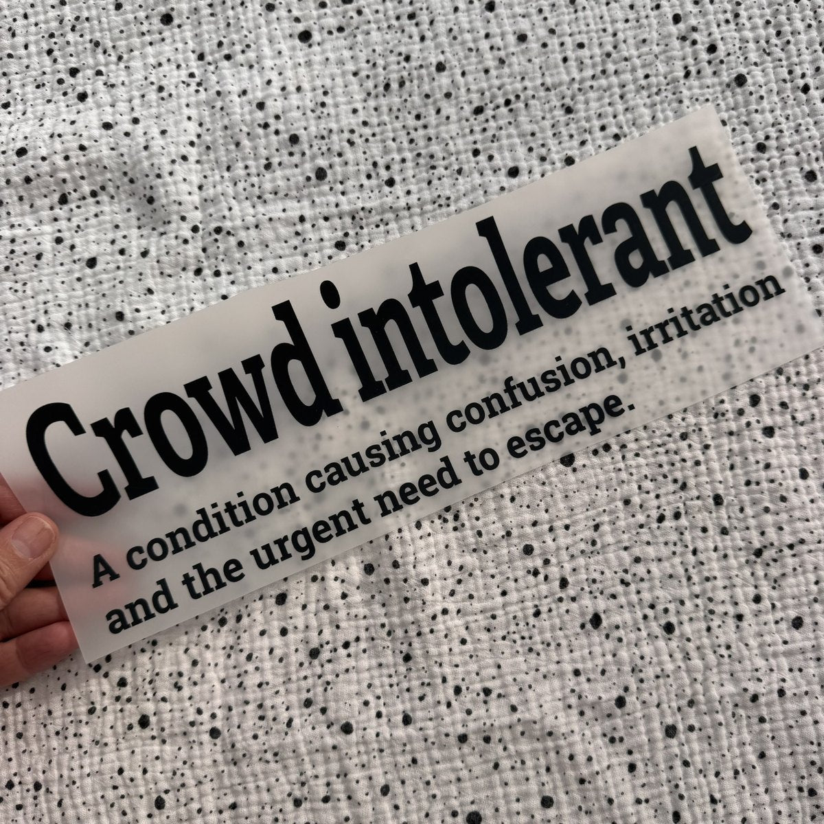 Bügelbild Crowd intolerant groß in Schwarz, ca. 29 x 9,5 cm, in der Hand gehalten
