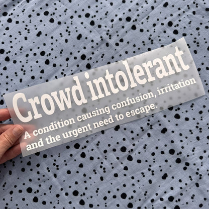 Bügelbild Crowd intolerant groß in Weiß, ca. 29 x 9,5 cm, in der Hand gehalten
