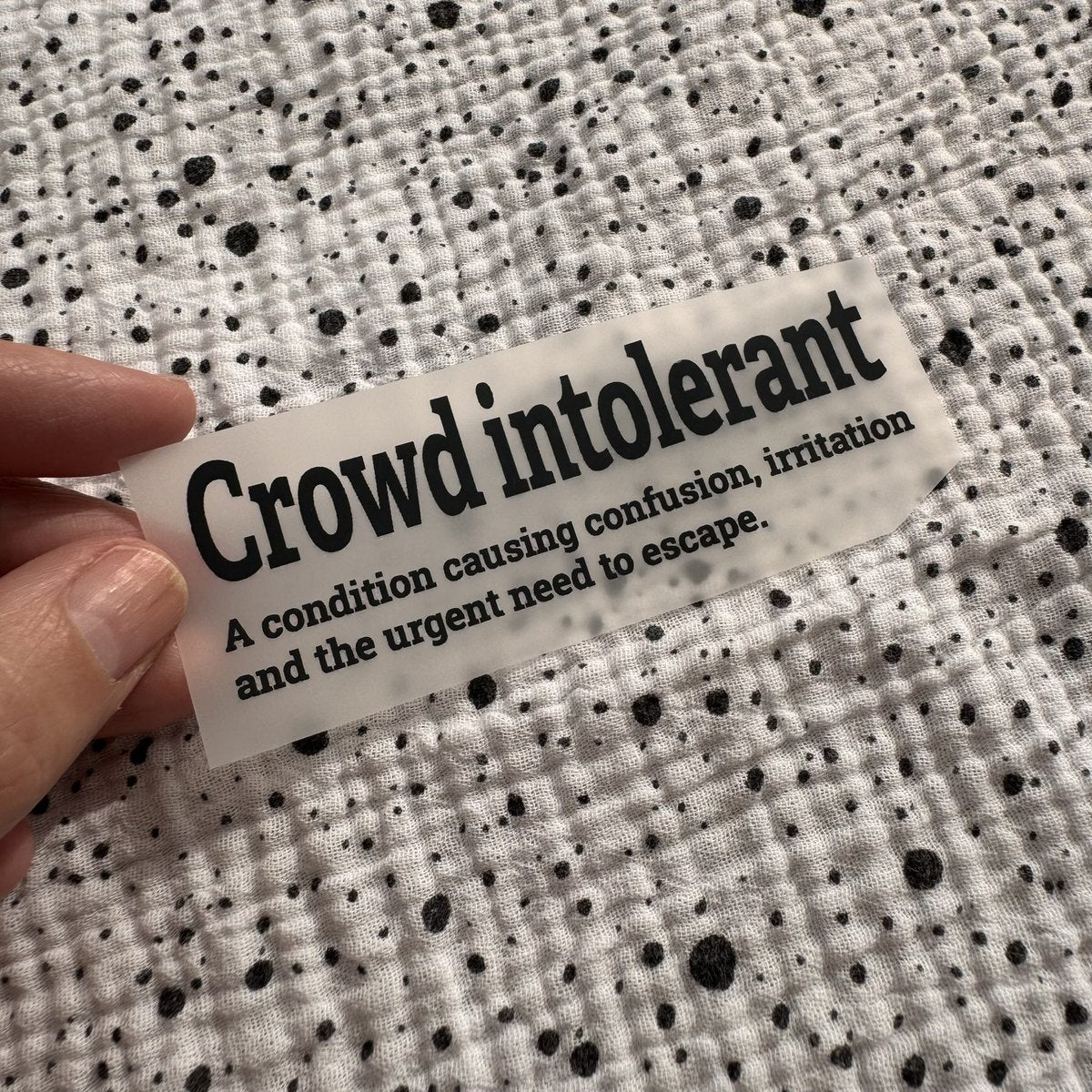 Bügelbild Crowd intolerant klein in Schwarz, ca. 10 x 3 cm, in der Hand gehalten
