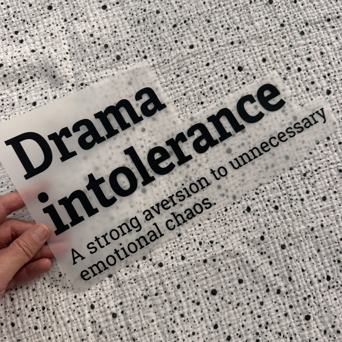 Bügelbild Drama intolerance groß in Schwarz, ca. 29,5 x 15,5 cm, in der Hand gehalten