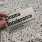 Bügelbild Drama intolerance klein in Schwarz, ca. 10 x 5 cm, in der Hand gehalten