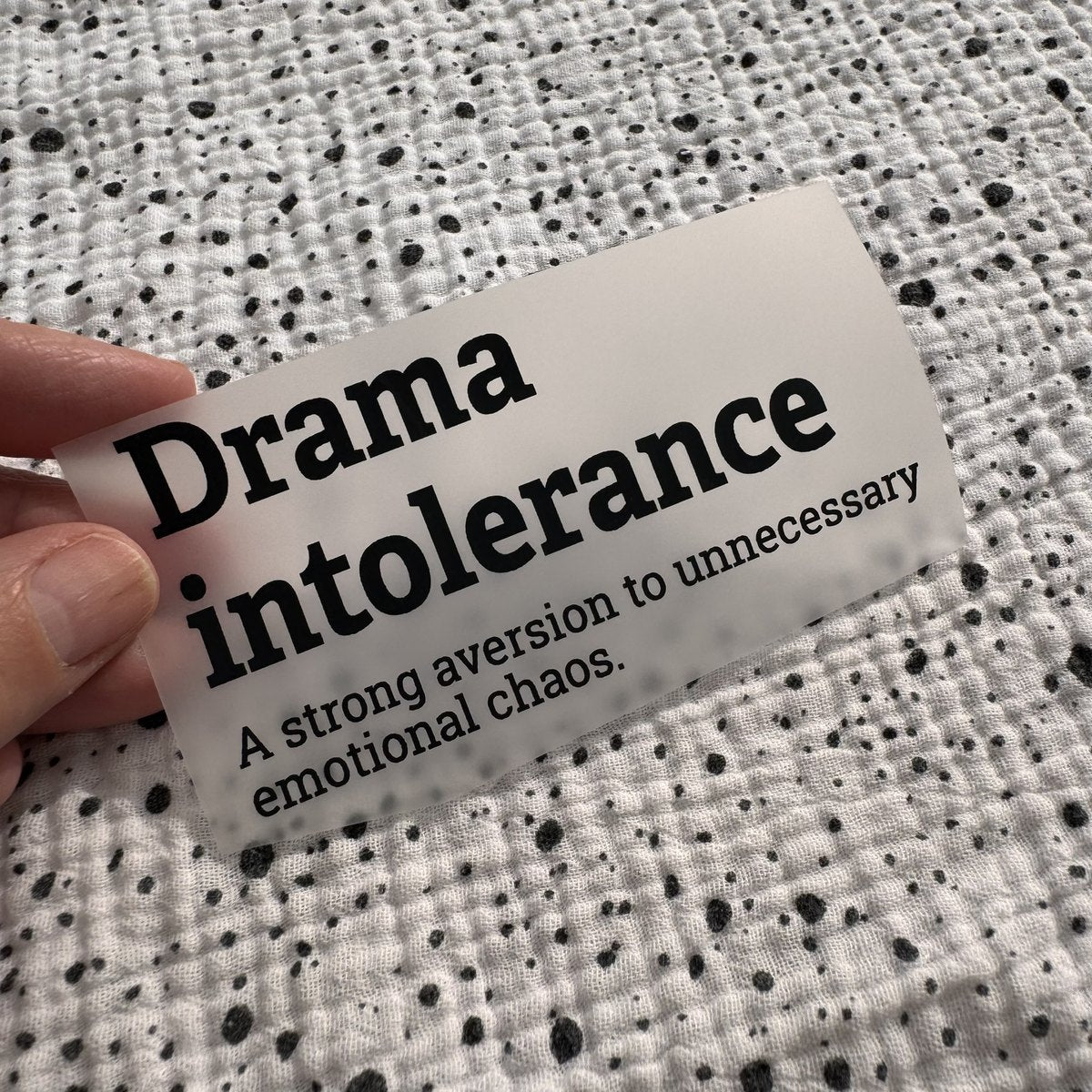 Bügelbild Drama intolerance klein in Schwarz, ca. 10 x 5 cm, in der Hand gehalten