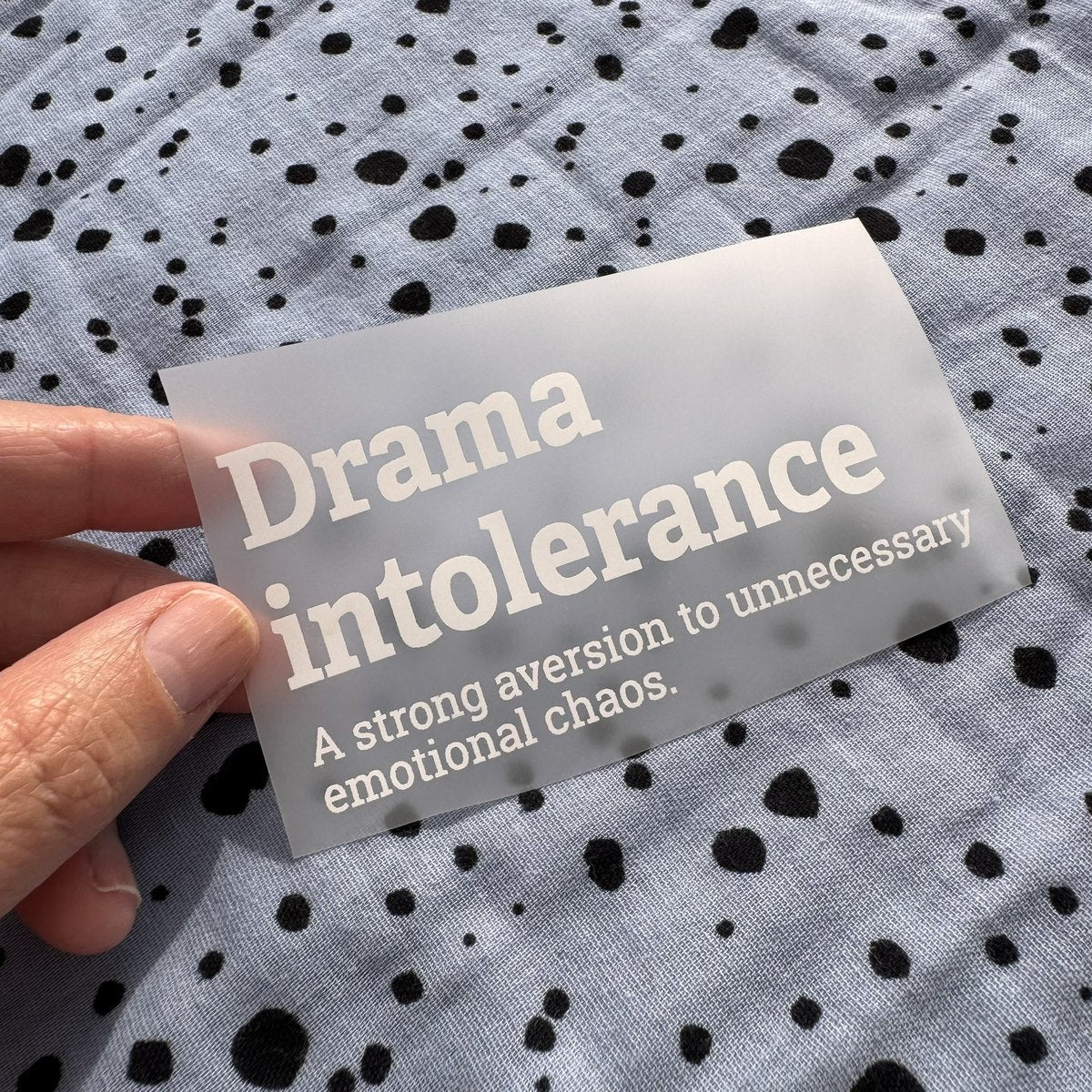 Bügelbild Drama intolerance klein in Weiß, ca. 10 x 5 cm, in der Hand gehalten