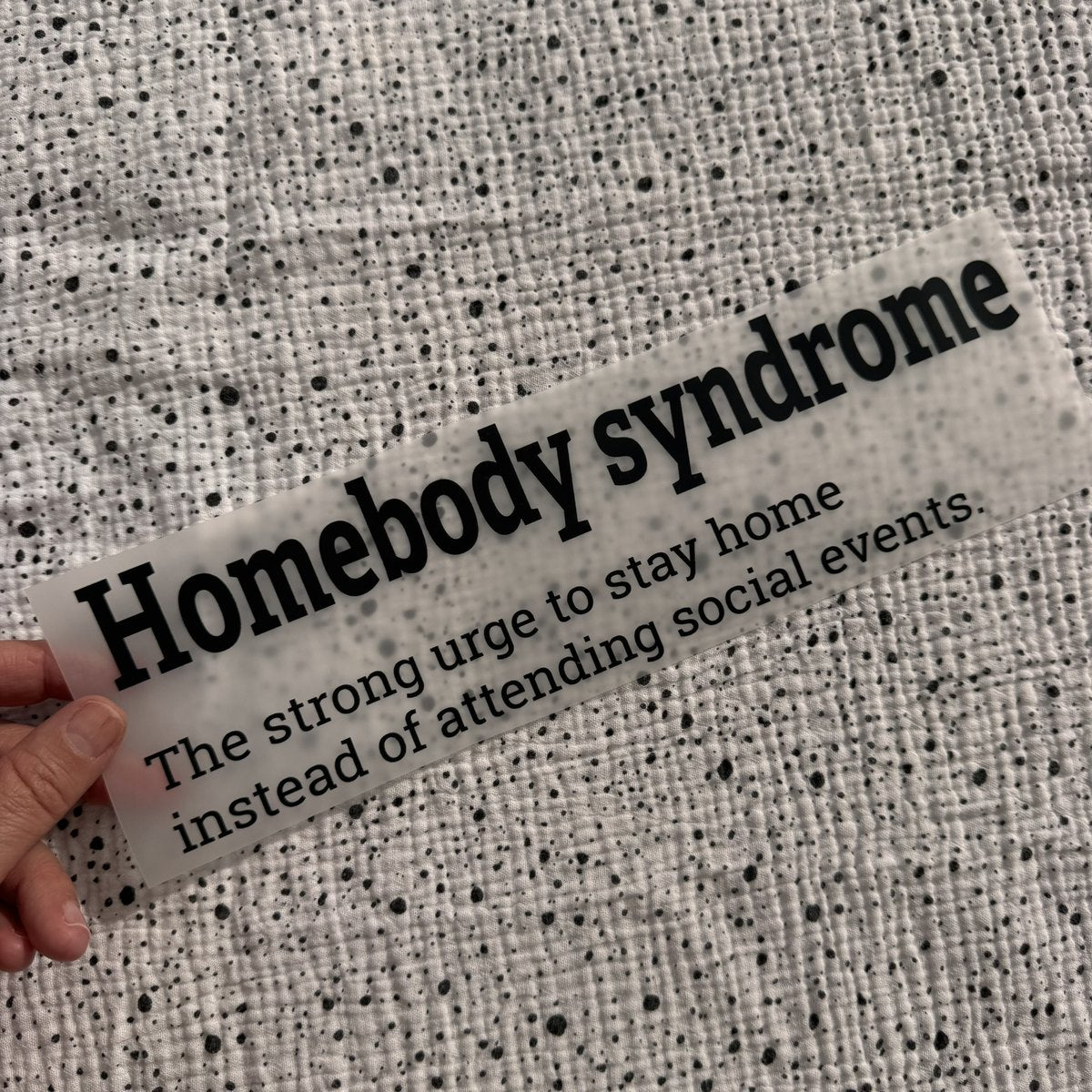 Bügelbild Homebody syndrome groß in Schwarz, ca. 29,5 x 8,5 cm, in der Hand gehalten