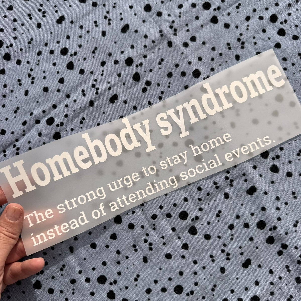 Bügelbild Homebody syndrome groß in Weiß, ca. 29,5 x 8,5 cm, in der Hand gehalten