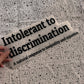 Bügelbild Intolerant to discrimination groß in Schwarz, ca. 32 x 13 cm, in der Hand gehalten