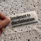 Bügelbild Intolerant to discrimination klein in Schwarz, ca. 10,5 x 4,5 cm, in der Hand gehalten