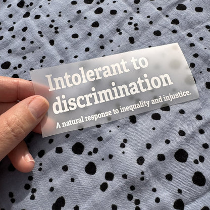 Bügelbild Intolerant to discrimination klein in Weiß, ca. 10,5 x 4,5 cm, in der Hand gehalten