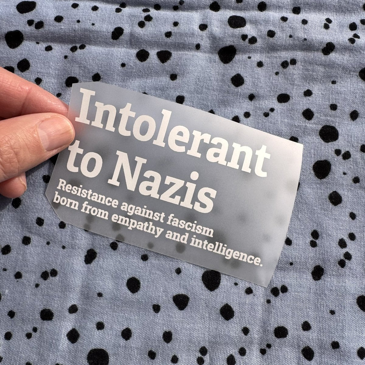 Bügelbild Intolerant to Nazis klein in Weiß, ca. 10 x 5,5 cm, in der Hand gehalten