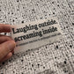 Bügelbild Laughing outside, screaming inside klein in Schwarz, ca. 10 x 4 cm, in der Hand gehalten