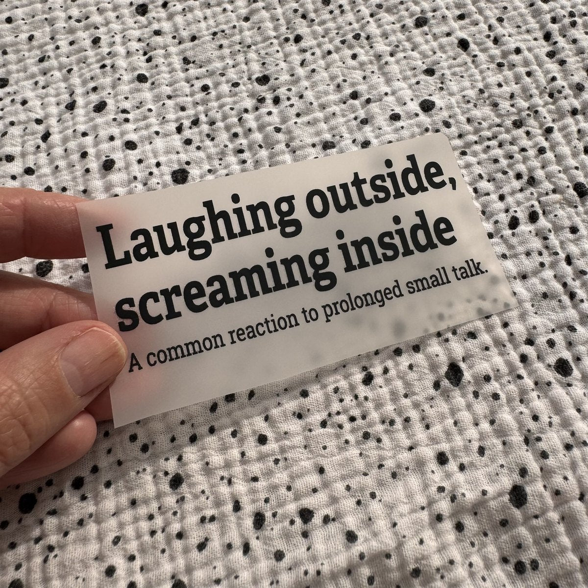 Bügelbild Laughing outside, screaming inside klein in Schwarz, ca. 10 x 4 cm, in der Hand gehalten