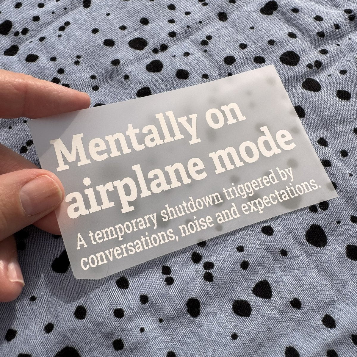 Bügelbild Mentally on airplane mode klein in Weiß, ca. 10 x 5,5 cm, in der Hand gehalten