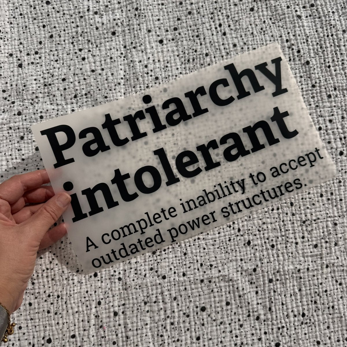 Bügelbild Patriarchy intolerant groß in Schwarz, ca. 29,5 x 17,5 cm, in der Hand gehalten