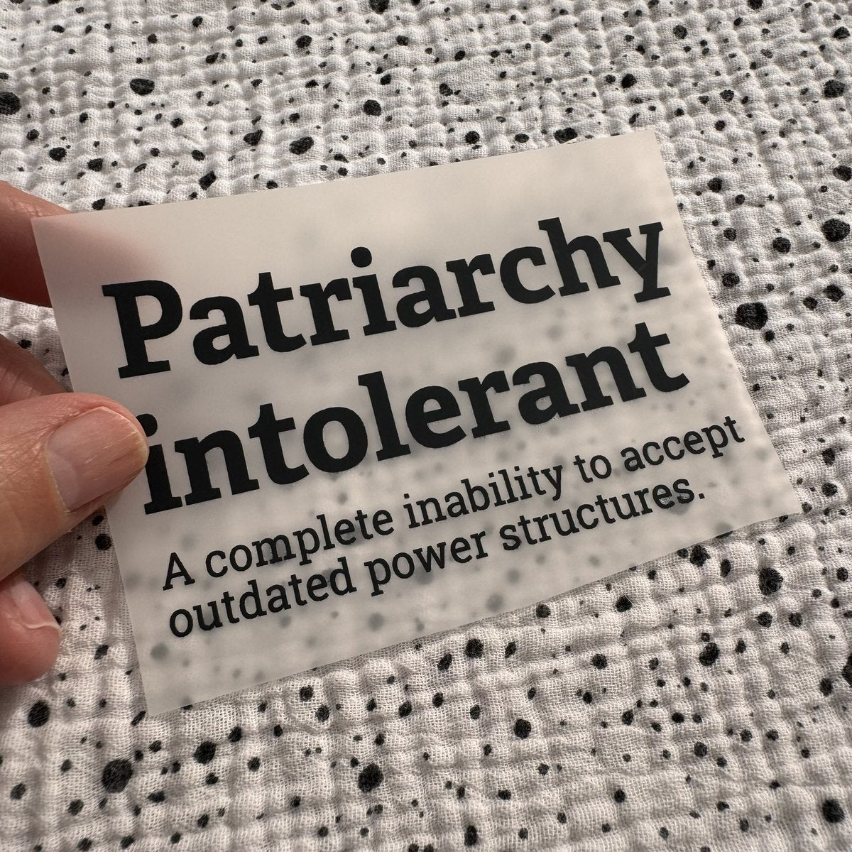 Bügelbild Patriarchy intolerant klein in Schwarz, ca. 10 x 6 cm, in der Hand gehalten
