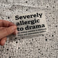 Bügelbild Severely allergic to drama klein in Schwarz, ca. 9,5 x 6,5 cm, in der Hand gehalten