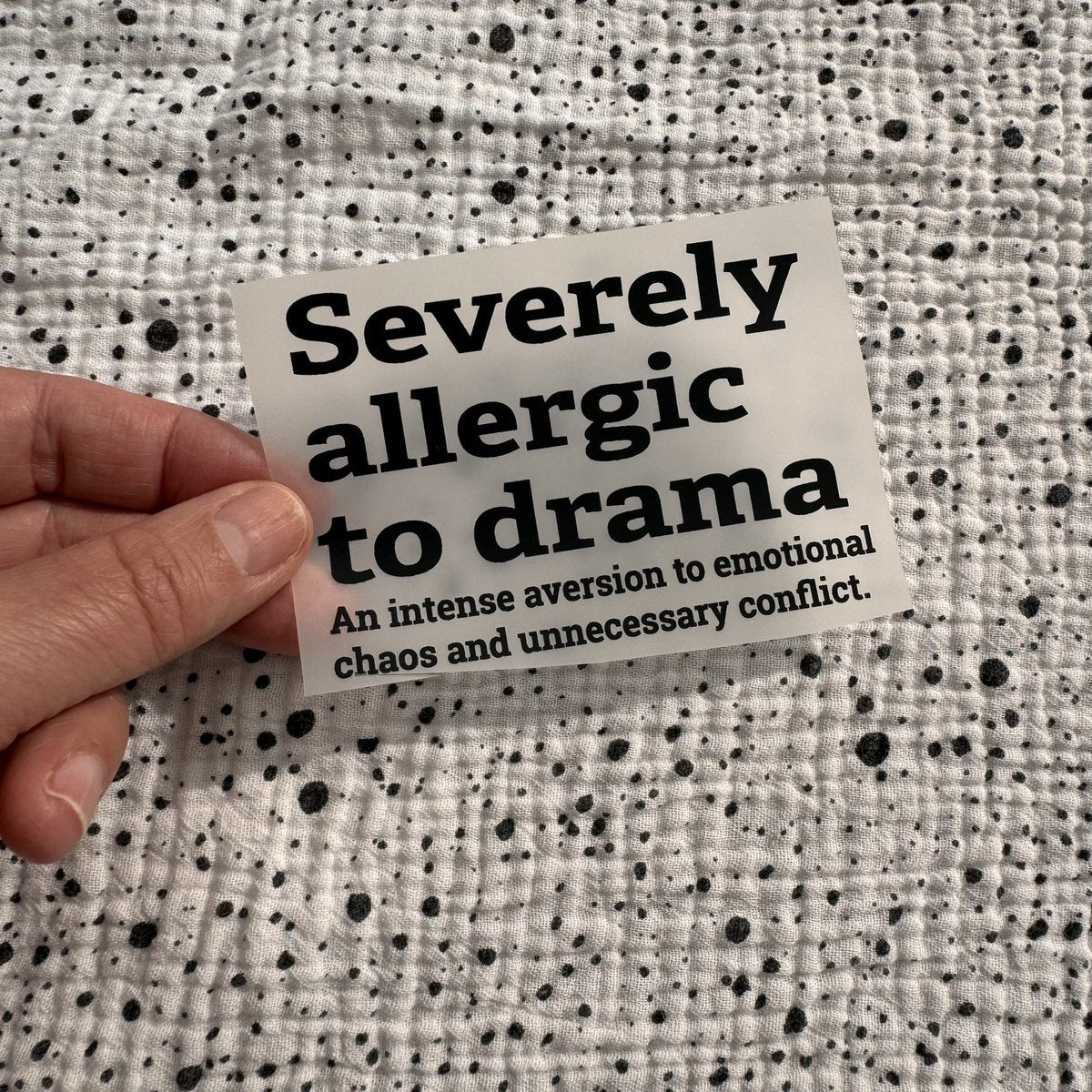 Bügelbild Severely allergic to drama klein in Schwarz, ca. 9,5 x 6,5 cm, in der Hand gehalten
