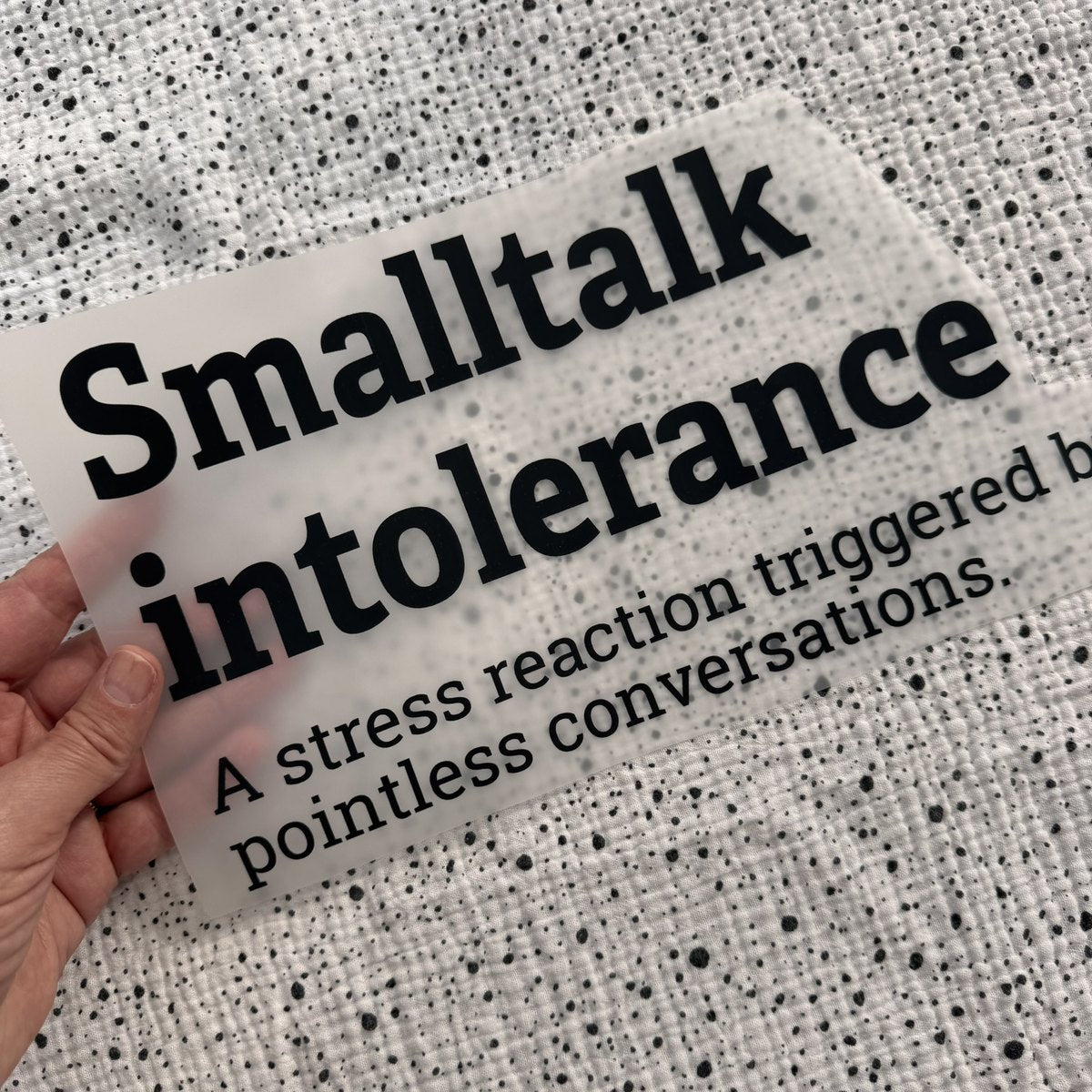 Bügelbild Smalltalk intolerance groß in Schwarz, ca. 29 x 16 cm, in der Hand gehalten