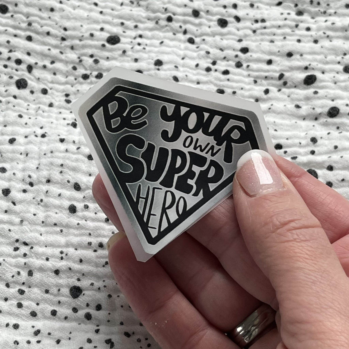 Bügelbild Super Hero in Silber – Superhelden-Wappen, in der Hand gehalten