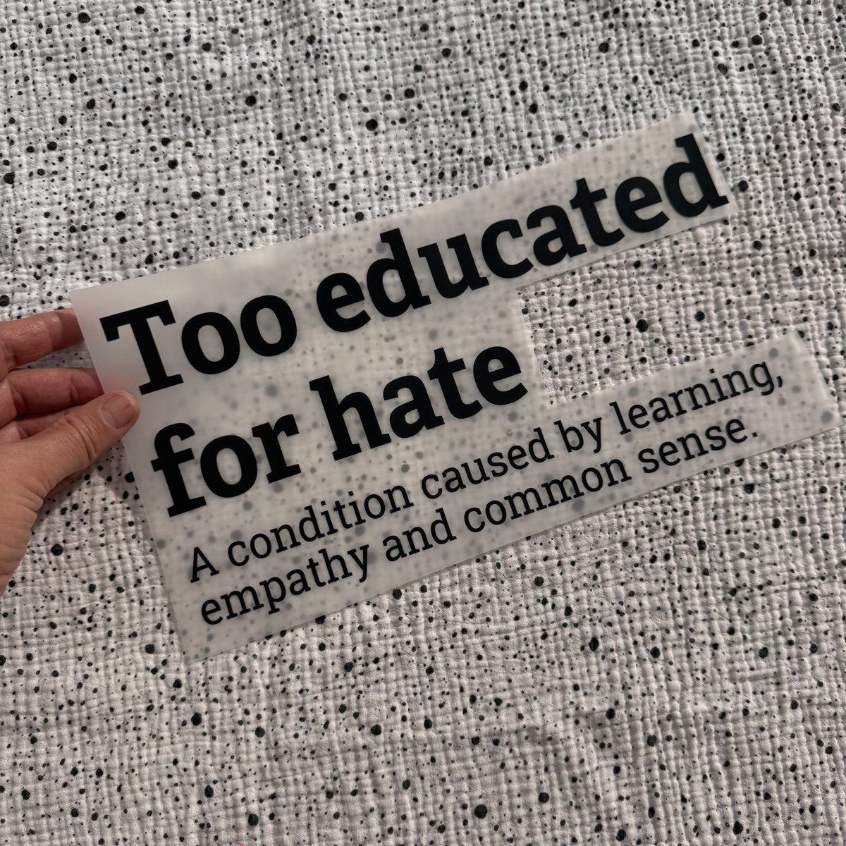 Bügelbild Too educated for hate groß in Schwarz, ca. 29,5 x 15 cm, in der Hand gehalten