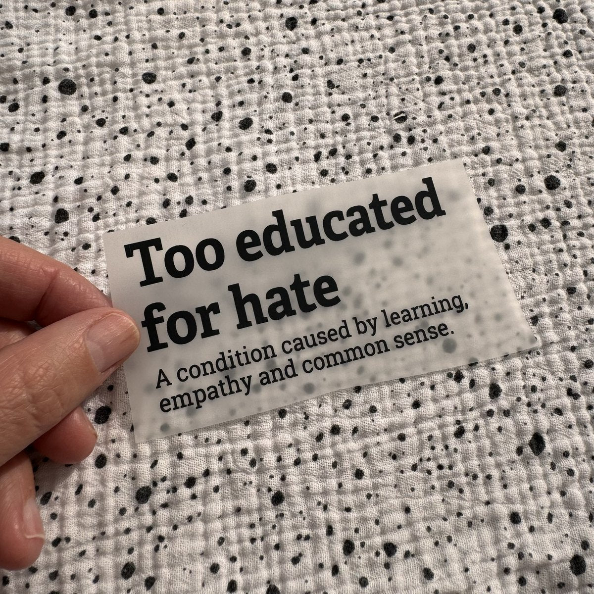 Bügelbild Too educated for hate klein in Schwarz, ca. 9,7 x 5 cm, in der Hand gehalten