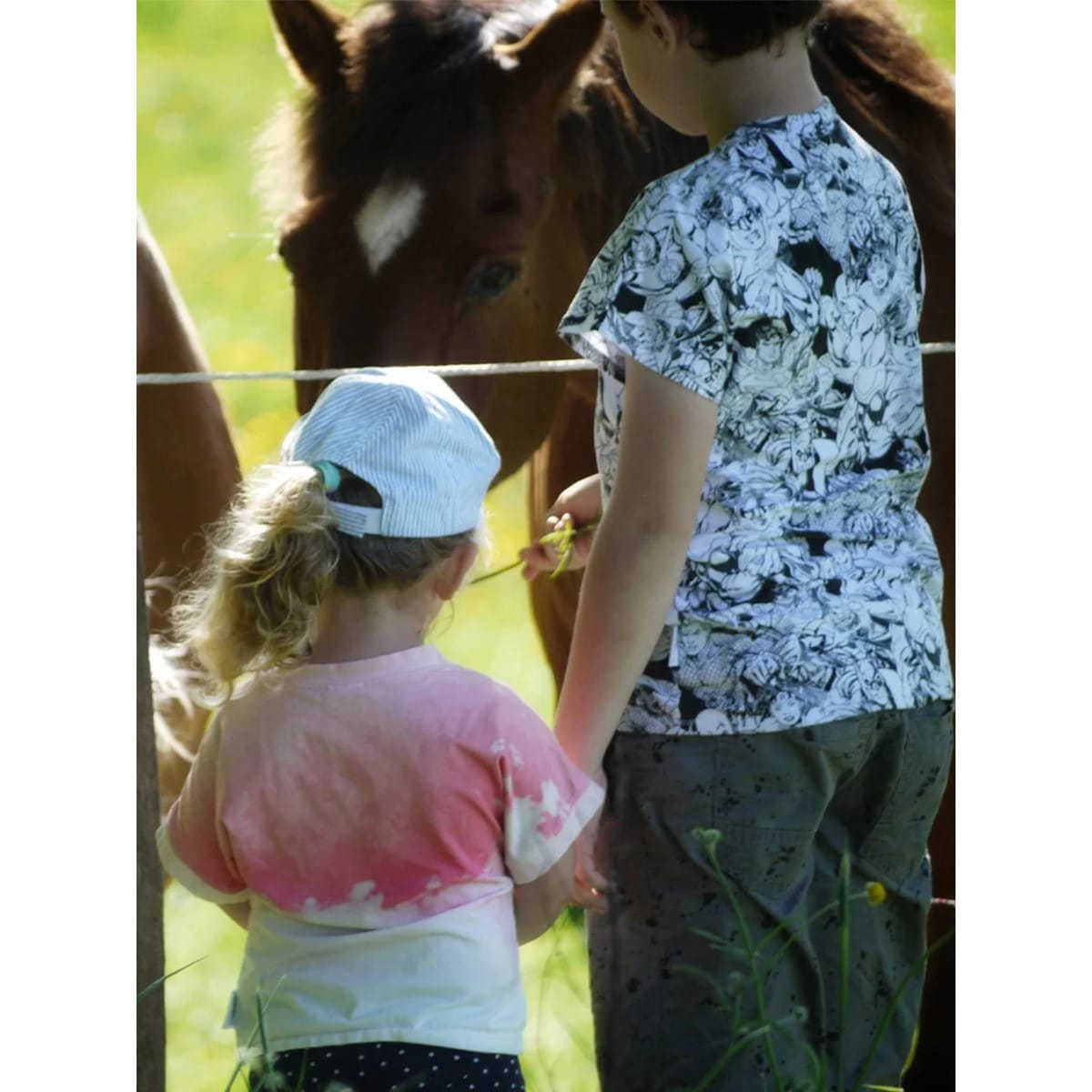 Zwei Geschwister am Pferdezaun im Family Shirt Kids mit Comic- und Batik-Print