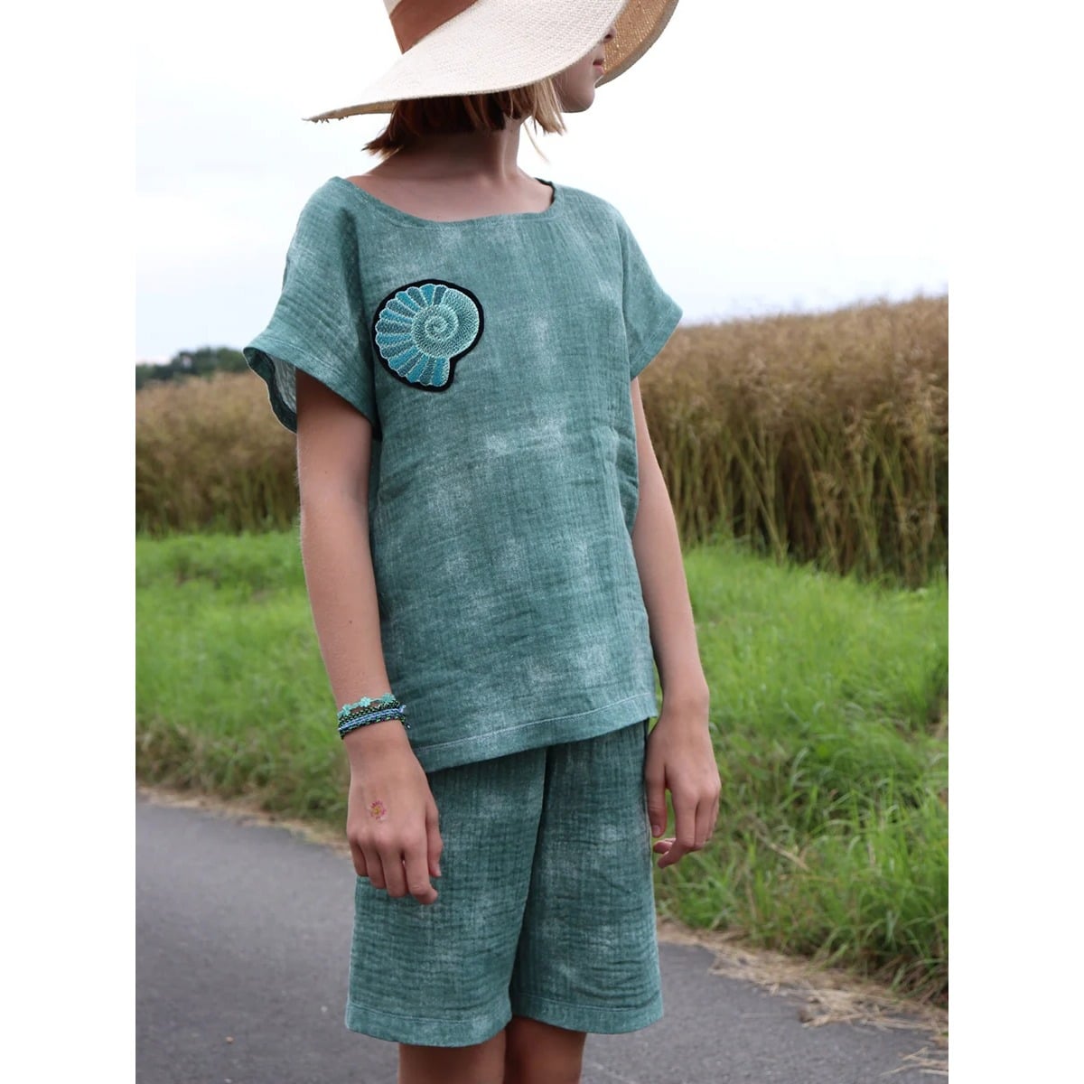 Kind im grünen Family Shirt Kids aus Musselin mit aufgesticktem Muschel-Motiv und passender Hose. Folienstickdatei Muschel aus Stickdatei Muscheln und Seesterne