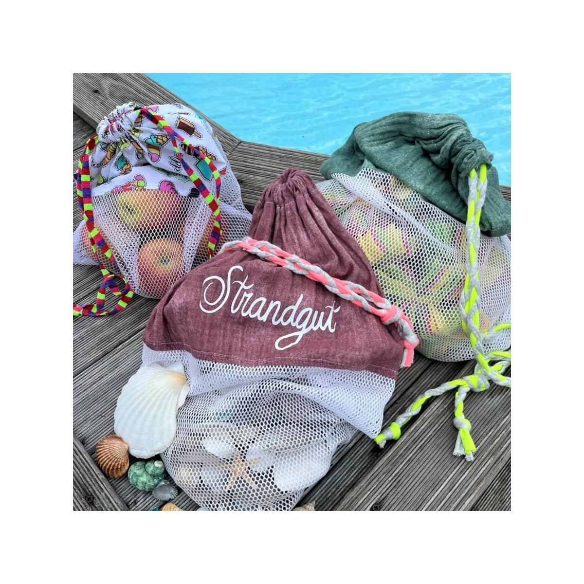 Freebook Sammelbeutel Strandgut – drei selbstgenähte Netzbeutel mit Äpfeln, Muscheln und Wasserbomben auf einem Holzsteg