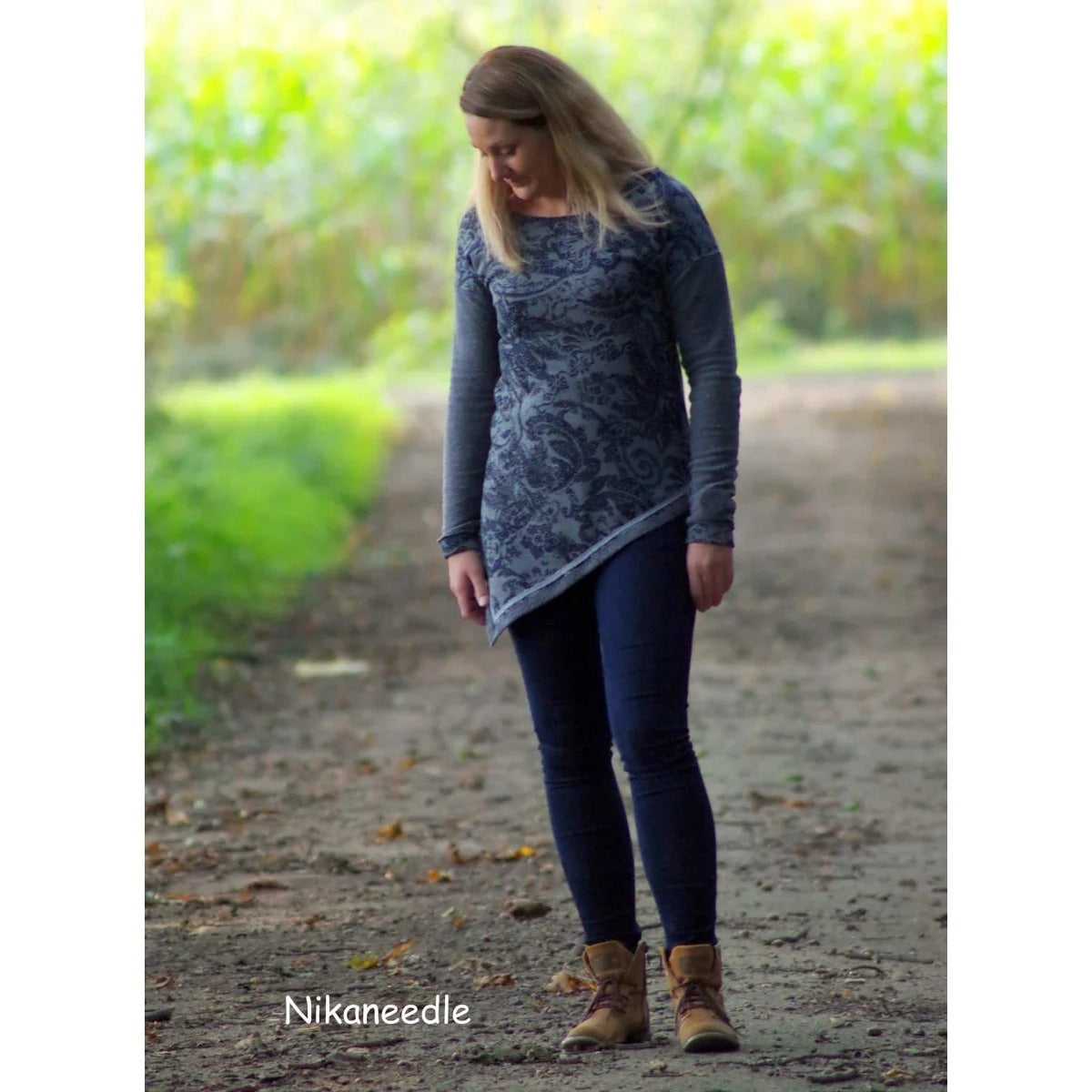 One Tip Shirt Schnittmuster – Frau im grauen One Tip Shirt mit Zipfelsaum auf einem Waldweg (genähtes Designbeispiel)