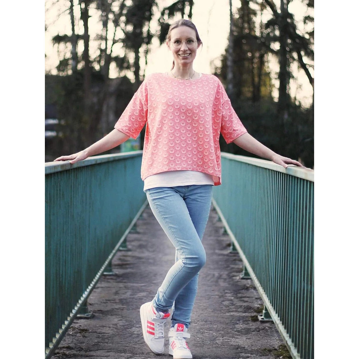 Oversized Pulli Schnittmuster Damen – rosa Pulli mit Blumenmuster und kurzen Ärmeln, getragen auf einer Brücke