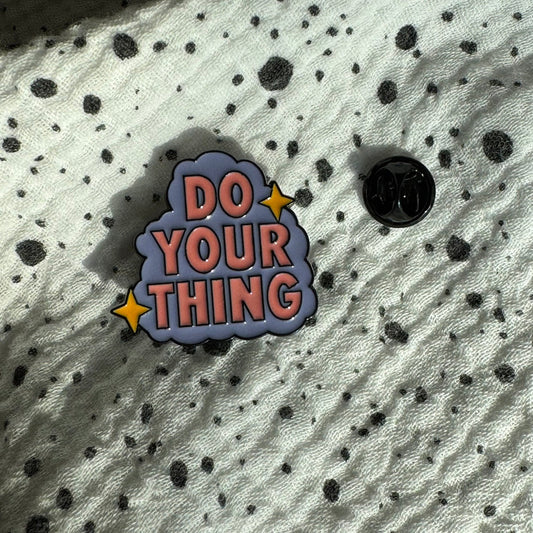 Emaille-Pin „Do your thing“ auf gepunktetem Stoff, daneben der Pin-Verschluss