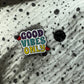 Emaille-Pin „Good Vibes Only“ auf gepunktetem Stoff, daneben der Pin-Verschluss