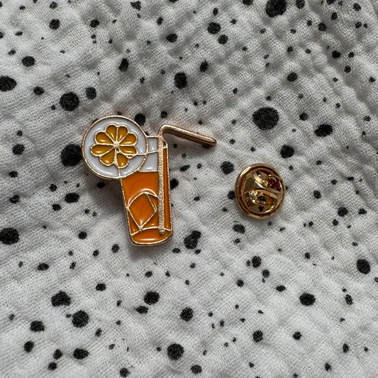 Emaille-Pin „Limonade“ auf gepunktetem Stoff, daneben der Pin-Verschluss