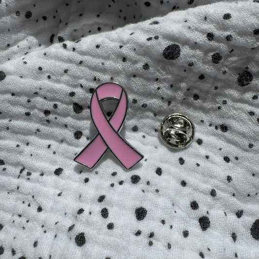 Emaille-Pin „Pink Ribbon“ silber auf gepunktetem Stoff, daneben der Pin-Verschluss